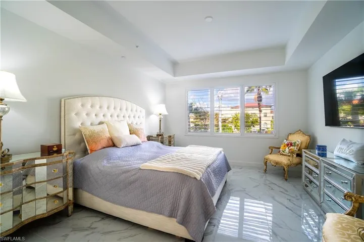 Bedroom with light marble finish flooring and a raised ceiling
