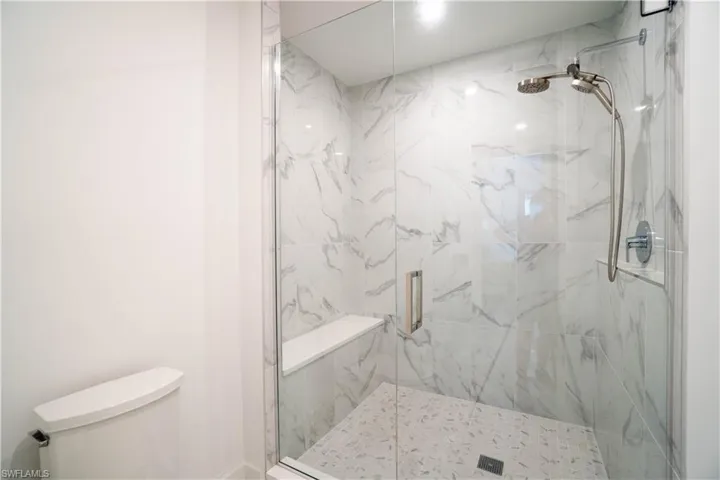 Bathroom featuring a marble finish shower and toilet
