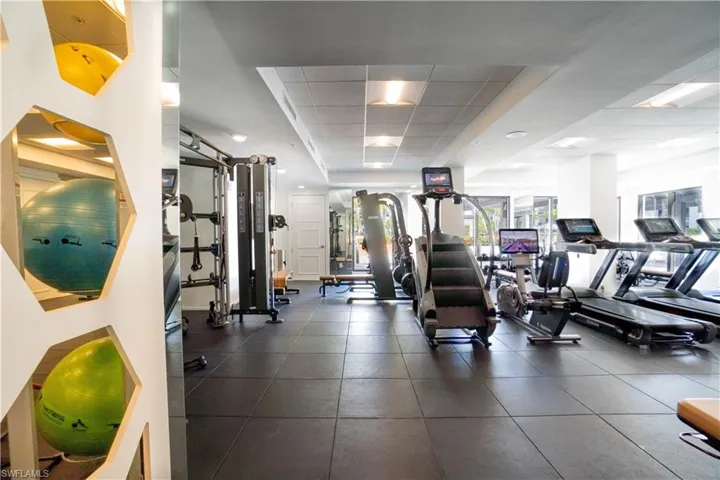 Fitness center featuring rubber flooring, recessed lighting, and a variety of exercise equipment including treadmills, stair climbers, and weight machines