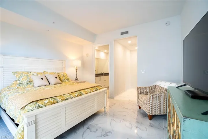 Bedroom featuring ensuite bath and light marble finish floors