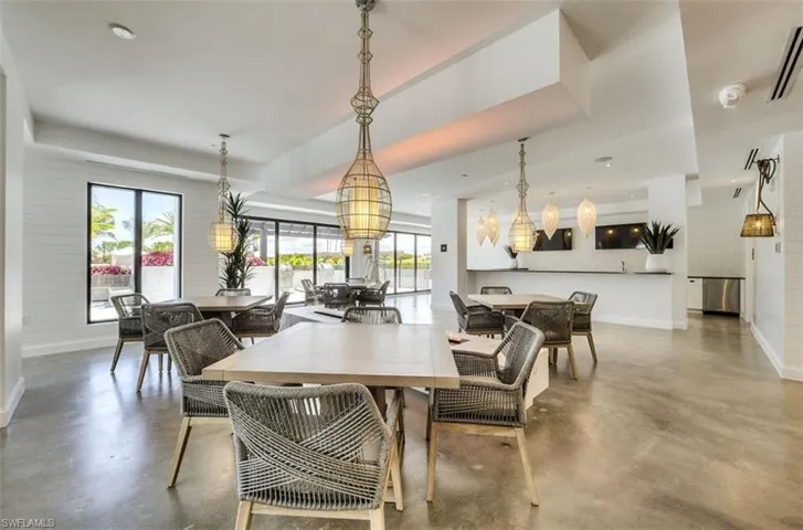 Interior gathering space featuring concrete-finish flooring, multiple dining areas, and a service bar with stainless steel appliances