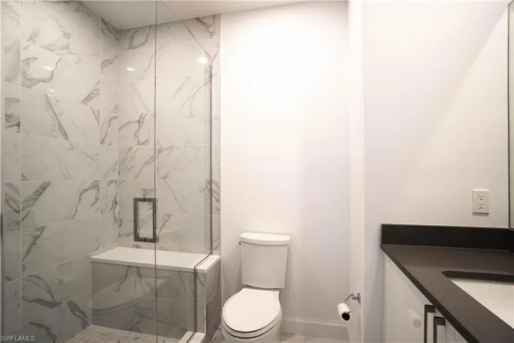Bathroom with vanity and a marble finish shower