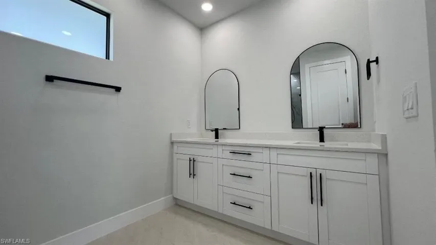 Full bathroom with double vanity, a sink, and baseboards