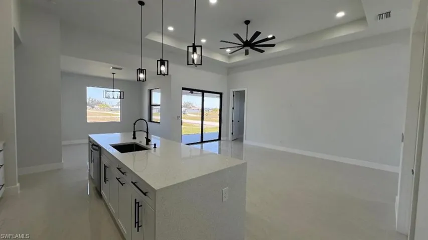 Kitchen featuring a tray ceiling, open floor plan, visible vents, and a sink