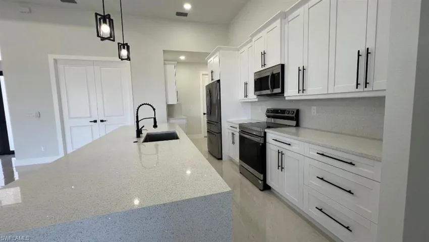 Kitchen with a sink, white cabinetry, appliances with stainless steel finishes, visible vents, and decorative backsplash