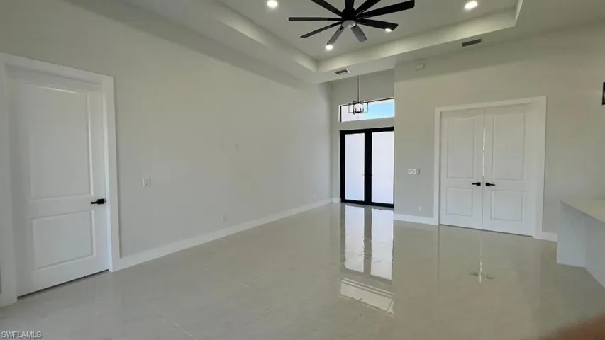 Empty room featuring baseboards, visible vents, ceiling fan with notable chandelier, and a raised ceiling