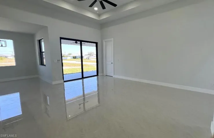 Empty room with baseboards, ceiling fan, recessed lighting, and a towering ceiling