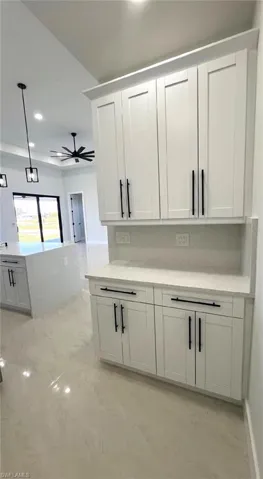 Kitchen with marble finish floor, ceiling fan, recessed lighting, white cabinetry, and pendant lighting