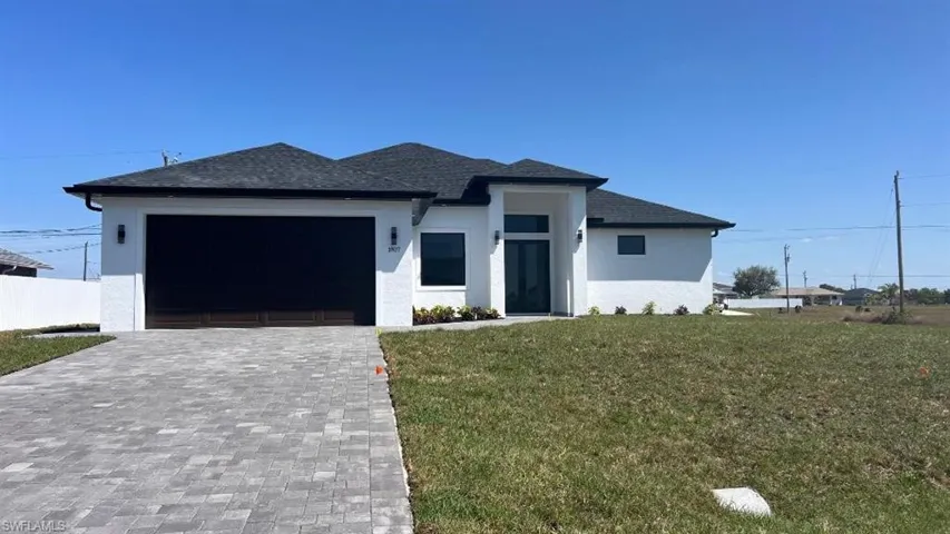 Prairie-style home featuring roof with shingles, stucco siding, a front lawn, decorative driveway, and a garage