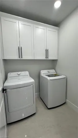 Laundry area featuring baseboards, cabinet space, and separate washer and dryer