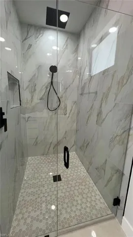 Full bath with a marble finish shower