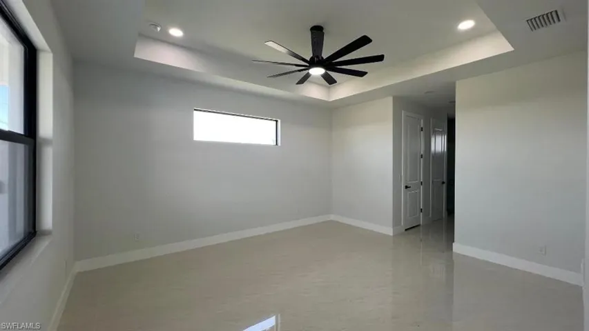 Empty room featuring baseboards, ceiling fan, visible vents, and a raised ceiling