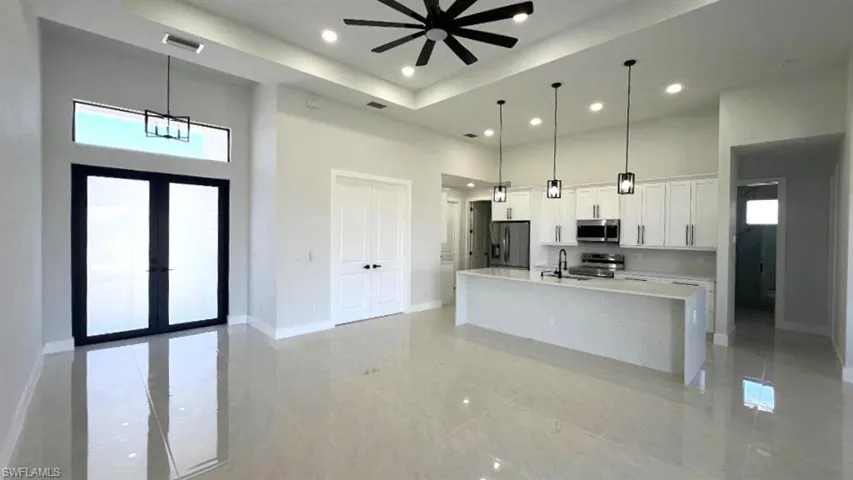 Kitchen with visible vents, light countertops, a towering ceiling, and appliances with stainless steel finishes