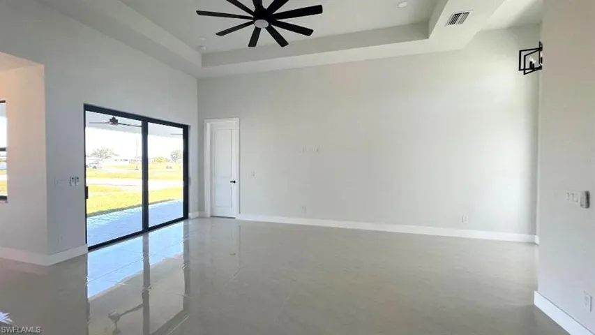 Spare room featuring visible vents, a tray ceiling, baseboards, and ceiling fan