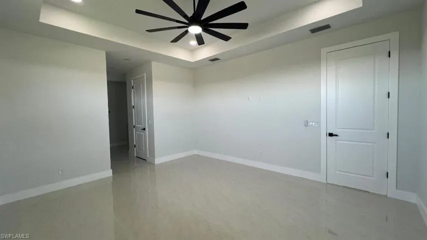 Spare room with a tray ceiling, baseboards, visible vents, ceiling fan, and recessed lighting