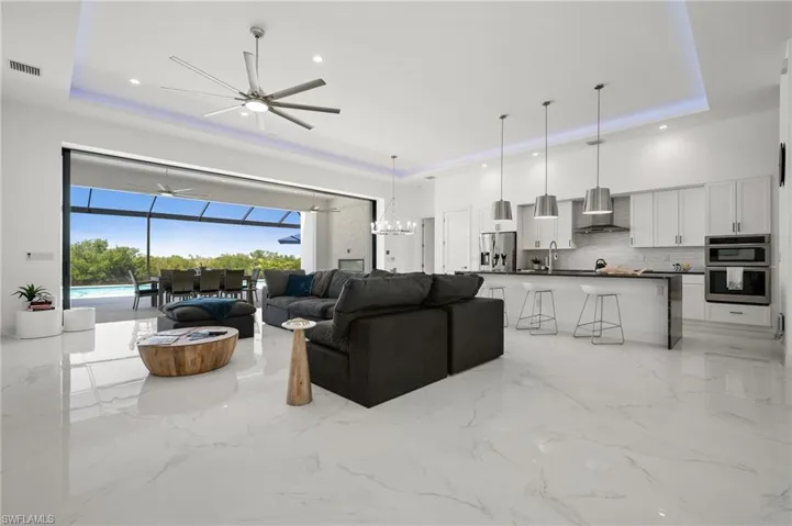 Living room featuring a sunroom, ceiling fan, a raised ceiling, and recessed lighting