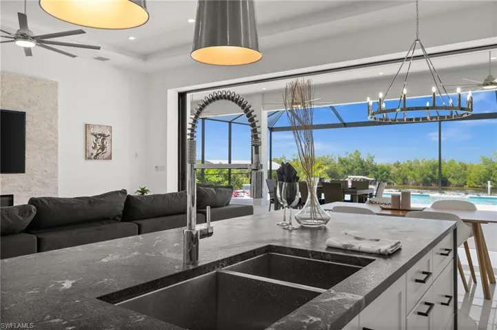Kitchen featuring ceiling fan, open floor plan, hanging lights, and dark stone countertops