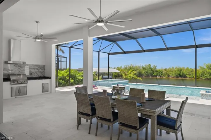 View of patio featuring an outdoor kitchen / dining area, glass enclosure, a ceiling fan, a pool with connected hot tub, and a sunroom