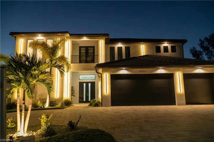 View of front of home with a balcony, stucco siding, and driveway