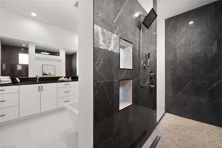 Bathroom with a marble finish shower, vanity, light marble finish floors, and a soaking tub