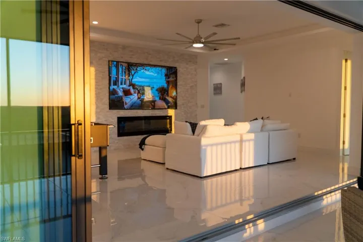 Cinema featuring marble tiled flooring, a ceiling fan, recessed lighting, and a glass covered fireplace