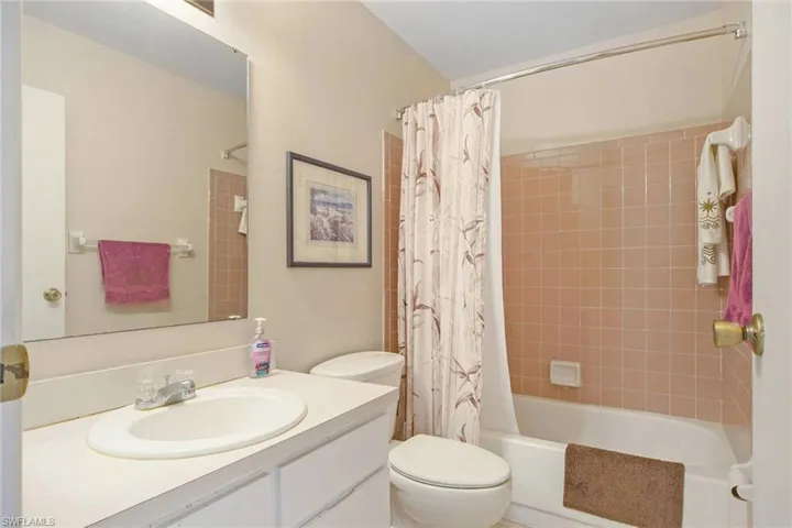 Bathroom featuring shower / bath combo with shower curtain, toilet, and vanity