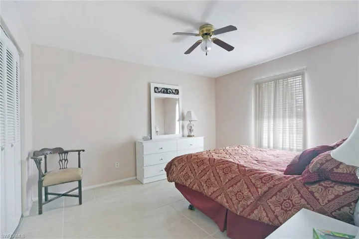 Bedroom featuring light tile floors, baseboards, a ceiling fan, and a closet