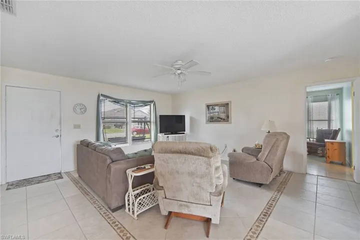 Living area with light tile  floors, plenty of natural light, and ceiling fan