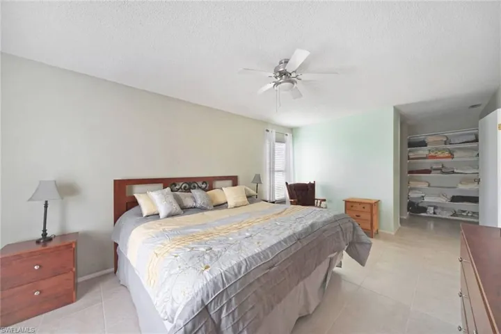 Bedroom with a closet, a textured ceiling, light tile flooring, and a spacious closet