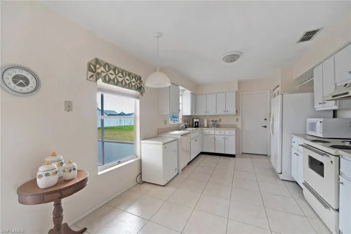 Kitchen with visible vents, light countertops, light tile patterned floors, white cabinets, and white appliances