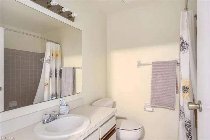 Full bathroom featuring curtained shower, toilet, and vanity