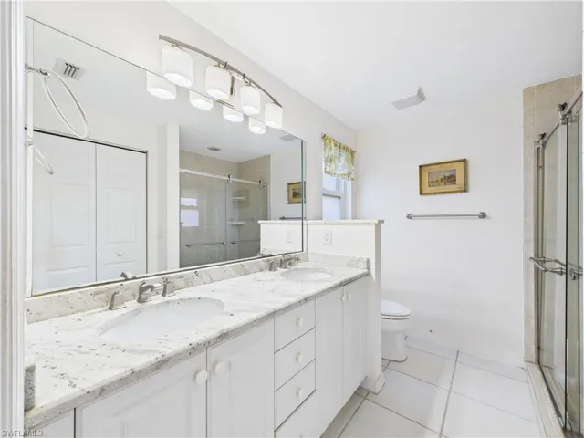 Full bathroom featuring double vanity, a stall shower, a sink, and tile patterned floors