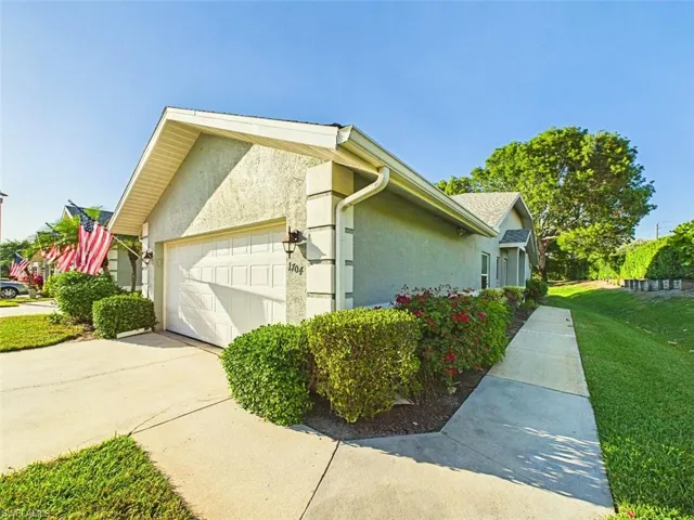 View of side of home with an attached garage, concrete driveway, stucco siding, and a yard