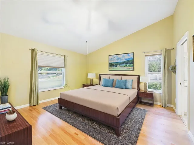 Bedroom featuring light wood-style flooring, baseboards, and lofted ceiling