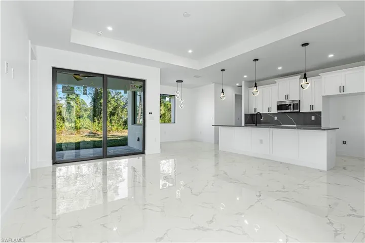 Kitchen featuring a tray ceiling, decorative backsplash, white cabinetry, and decorative light fixtures