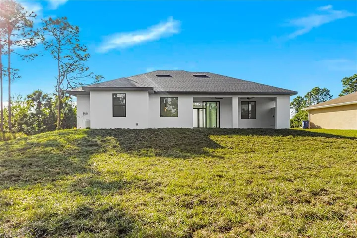 Back of house featuring ceiling fan and a yard