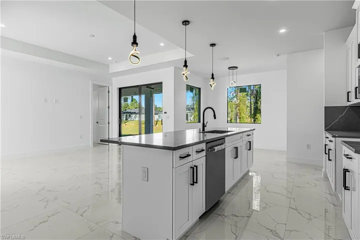 Kitchen with white cabinets, dishwasher, sink, and an island with sink