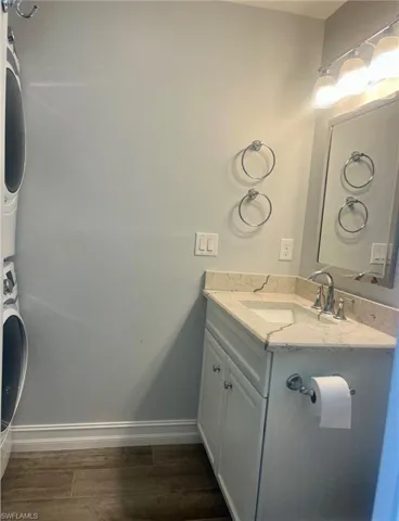 Bathroom with vanity, dark wood-style floors, and stacked washer / drying machine