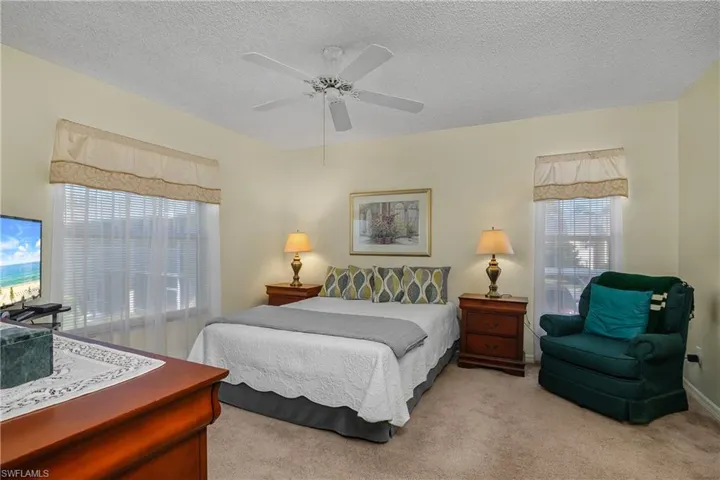 Bedroom with light carpet, a textured ceiling, and a ceiling fan