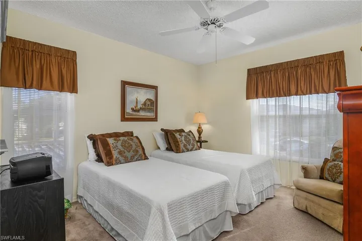 Carpeted bedroom featuring a textured ceiling and a ceiling fan