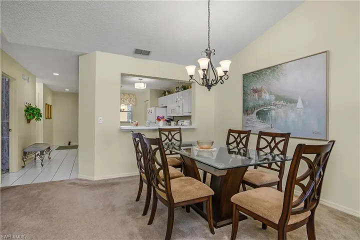 Dining room featuring light colored carpet, light tile patterned floors, a chandelier, a textured ceiling, and recessed lighting