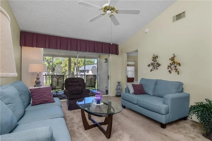 Carpeted living room with lofted ceiling, a textured ceiling, a ceiling fan, and a sunroom