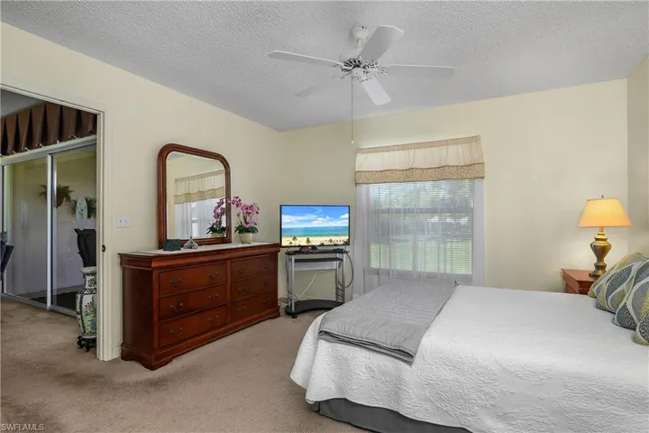 Carpeted bedroom featuring a textured ceiling and a ceiling fan
