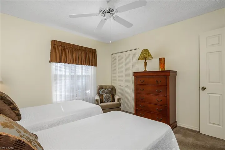 Carpeted bedroom with a textured ceiling, a ceiling fan, and a closet