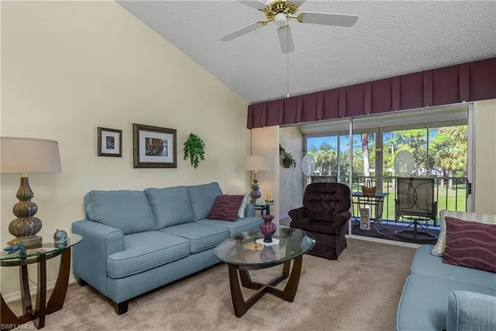 Living room with carpet flooring, a textured ceiling, a ceiling fan, and high vaulted ceiling