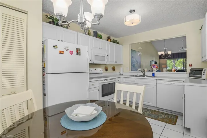 Kitchen featuring a chandelier, white appliances, light countertops, hanging light fixtures, and light tile patterned floors