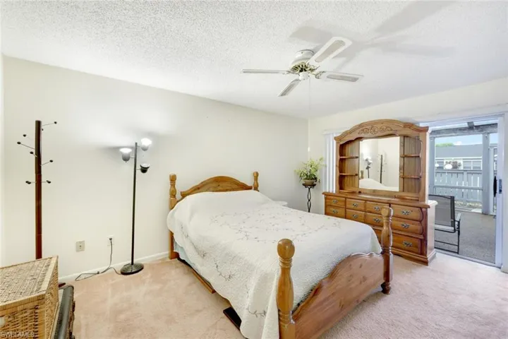 Carpeted bedroom featuring access to outside, a textured ceiling, and ceiling fan