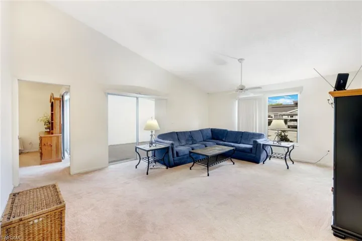 Carpeted living room featuring high vaulted ceiling and ceiling fan