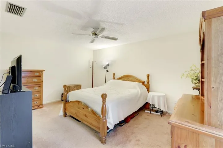 Carpeted bedroom featuring a textured ceiling and ceiling fan