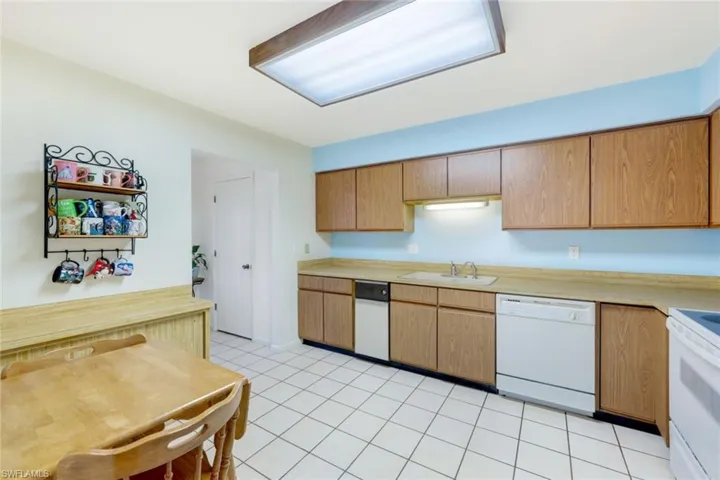 Kitchen with white appliances, sink, and light tile patterned flooring